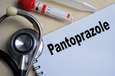 Pantoprazole kavramı, Tahta Masa 'da izole edilmiş bir kitap üzerine yazılmış. steteskop ve eczacılık
