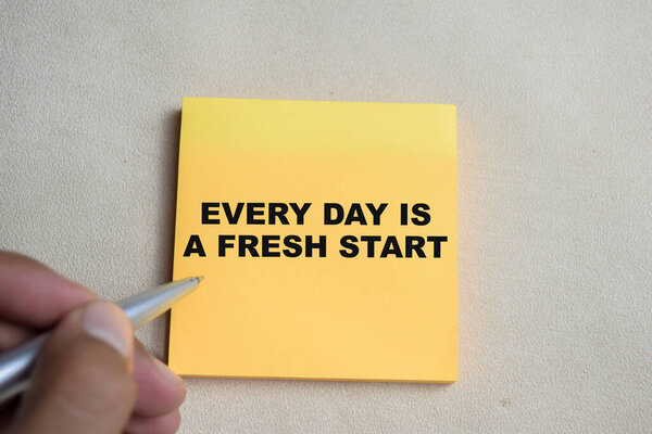 Concept of Every day is a fresh start write on sticky notes isolated on Wooden Table.