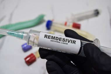 Remdesivir antiviral sıvı ilaç şırıngası siyah eldivenli ellerde. Tıbbi konsept