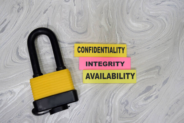 Concept of Key and confidentiality Integrity Availability - CIA write on sticky notes isolated on Wooden Table.