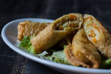 Marul yatağında ev yapımı börekler. Tahta bir arka planda beyaz bir tabakta