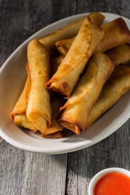 Çin tatlısı ve ekşi soslu ev yapımı börekler. Tahta bir arka planda beyaz bir tabakta