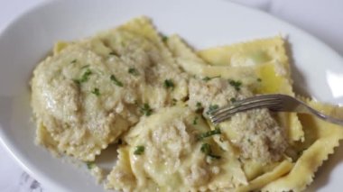 Kabak, havuç, patates ve enginar pesto ile tatlandırılmış ev yapımı ravioli doğrayan bir çatalın yakın çekimi.