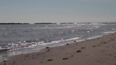 Sakin deniz dalgalarına yakın çekim. Arka planda kayalar var. Nisan 2023 'te rahatlatıcı bir gün.