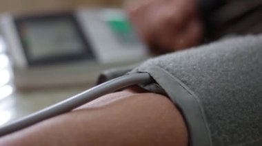 Kan basıncı monitörünün yakın plan görüntüsü. Yaşlı kadının kolunda tansiyon göstergesi var. Evde dijital tonometre kullanmak. Sağlık, hastalık tedavi kavramı.