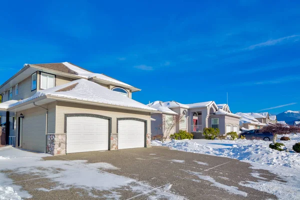 stock image Double garage of big luxury house with driveway and front yard in snow. Street of residential houses on winter sunny day