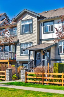 Residential townhouse entries with wooden fence in front on early sprint day in Vancouver, Canada