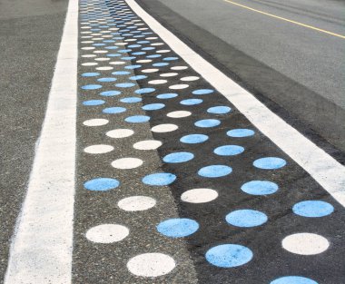 Asfalt yoldaki yaya geçidi mavi ve beyaz noktalarla boyanmış..