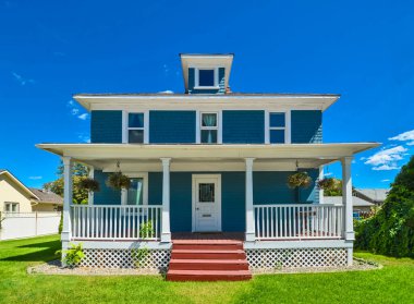 Historic residential house with church porch and doorsteps in front. Big family house with green lawn in front and blue sky background. Kelowna, British Columbia, Canada.