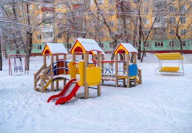 Arka planda ikametgah binası olan çocuklar karda oynuyorlar. Krasnoyarsk şehrinde kış mevsimi