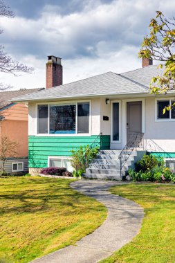 Güneşli bir günde ön bahçesinde beton yolu olan güzel bir evin ana girişi.