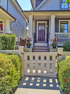 A perfect neighborhood. Porch and entrance door of a nice residential house with two flower pots in front.