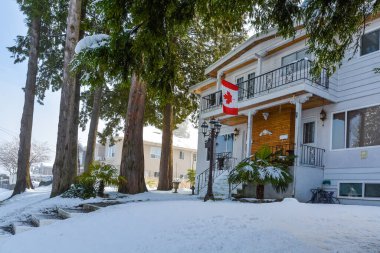 Duplex house on snowy day in winter. Duplex house with Canadian flag above the entrance clipart