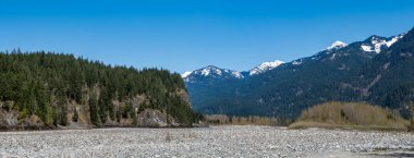 British Columbia 'daki Rocky dağlarının panoramik manzarası. Dağlarda taştan nehir yatağı