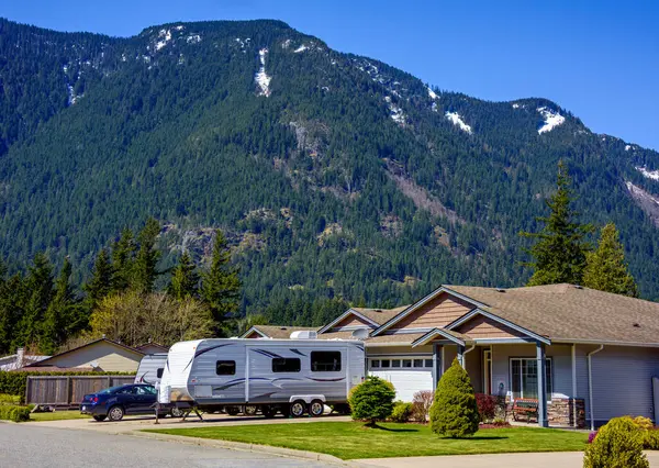 Yeni lüks bir ev, arabası ve karavanı olan, garaj yoluna park edilmiş. Dağdaki aile evi..