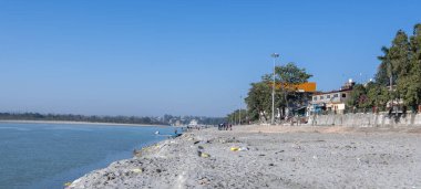 Rishikesh 'teki Triveni Ghaat' ın geniş açılı görüntüsü Ganj Nehri 'nin yakınında toplanan insanları gösteriyor..