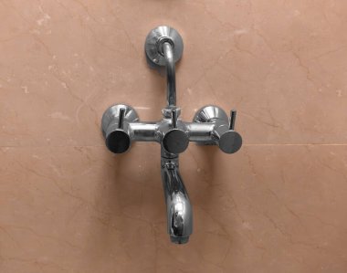 Sıcak ve soğuk su için krom metal bir musluk modern bir banyoda fayanslı bir duvara monte edilir. Yüzeydeki su damlaları temiz ve pürüzsüz görünümü arttırır..