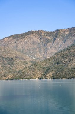 Tehri Gölü 'nün sakin mavi suları diğer taraftaki dağların görülebileceği sakin bir ortam sağlar. Huzurlu manzara ziyaretçileri bölgenin doğal güzelliğinin tadını çıkarmaya davet ediyor..