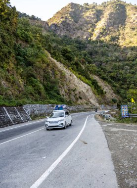 Rishikesh, Hindistan, 06 Aralık 2024: Tepesinde bavullarla dolu bir turist arabası dağ yolundan geçerken görülüyor, Rishikesh 'i keşfeden ziyaretçilerin yolculuğunu vurguluyor.