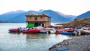 Tehri Gölü, Hindistan, 06 Aralık 2024: Tahri Gölü 'nde eski ve yeni teknelerle birlikte yüzen bir otel bulunmaktadır. Arka plandaki dağlar çarpıcı bir manzara sağlıyor..