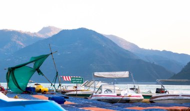 Tehri Gölü, Hindistan, 06 Aralık 2024: Eski tekneler, bir güvenlik levhası eşliğinde suda yüzüyor. Arka plandaki dağlar Tahri Gölü 'nün sakin çevresine katkıda bulunur..