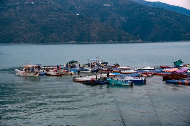 Tehri Lake, India  December 06, 2024: Boats are docked at the jetty at the lake, featuring a mix of old and new boats. These boats are waiting for tourists, highlighting the recreational activities available at Tehri Lake. clipart