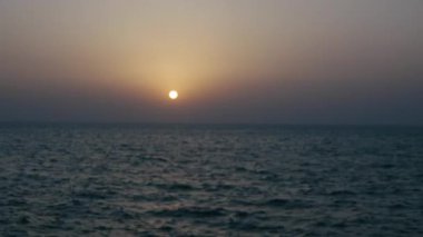 Denizde nefes kesen bir gün batımı, şiddetli dalgaların görüntüsüyle yükselen mavi dalgaların üzerine çağlayan güneş ışınlarını ortaya çıkarır..