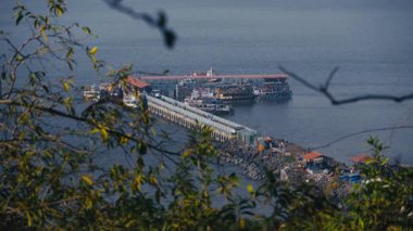Bir dağın tepesinden bakıldığında Fil Adası ve onun iskele manzarası görülebilir. Çok sayıda turist katamaran teknesi yakınlarda..