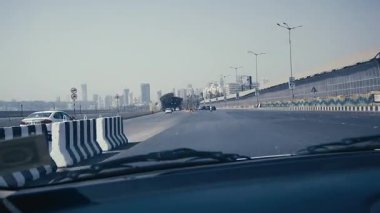 Mumbai şehrinin ufuk çizgisi denizin ötesinde, ihtişamını gözler önüne seriyor. Gemiler ve tekneler denizde özgürce dolaşarak hareketli aktiviteyi tamamlıyorlar. Güneş şehrin arkasında parlıyor, üzerinde kuşlar uçuşuyor..