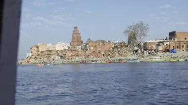 Nehrin karşısından, Vrindavan kasabasının geniş bir manzarası tapınakları, kasabayı, insanları ve tekneleri gösteriyor. Bu perspektif bölgenin resimsel ayarlarını vurgular.