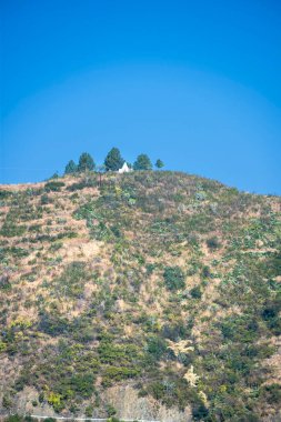 Yeşil kaplı bir dağ zirvesinde, çevresini saran manzaranın çarpıcı manzarasını sunan bir tapınağa sahiptir. Site ziyaretçileri keşif ve yansıtmaya çağırıyor.