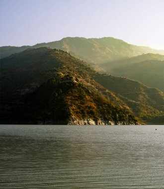 Sarı-kahverengi sabah ışığı yeşil dağların üzerine hafifçe düşer ve manzarayı aydınlatır. Sahne doğanın güzelliğini yakalıyor yeni bir güne uyanışını..