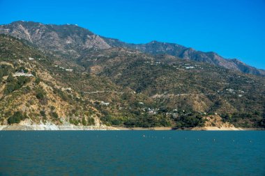 Dağlarda yuva yapmış küçük kasabalar, altta cazibelerini yansıtan bir göl var. Yüzen şamandıralar suya karakter katar, resim görünümünü güçlendirir.