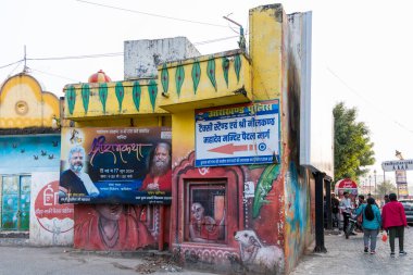 Rishikesh, Hindistan, 08 Aralık 2024: Rishikesh 'teki Mahadev tapınağına giden yol boyunca çeşitli tanrıların boyanmış duvarları ve posterleri. Bu sanatsal görüntü, bölgenin ruhani atmosferini arttırır..