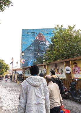 Rishikesh, Hindistan 8 Aralık 2024: Beatles Ashram in Rishikesh yolu Beatles grup üyelerinin posterleriyle süslenmiş duvarlar, canlı patika boyunca yürüyen insanlar.