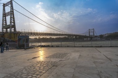 Rishikesh, Hindistan 08 Aralık 2024: Ganj Nehri 'nin karşı yakasından Janki Setu köprüsünün manzarası Rishikesh' teki bu ikonik simgeye benzersiz bir bakış açısı sunuyor.