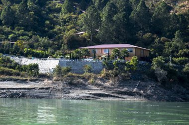 Göldeki manzaralı bir otel dağlar ve yeşil ağaçlar tarafından çerçevelenir. Doğal güzellik dinlenmek için mükemmel bir dinlenme yeri sunar..