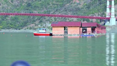 Tehri, Hindistan - 08 Ocak 2025: Göldeki yüzen barakalar huzurlu manzaranın dairesel bir görüntüsünü sunuyor. Sakin sular çevrenin güzelliğini yansıtır..
