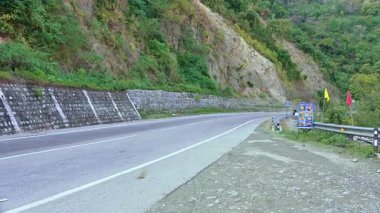 Rishikesh, Hindistan - 08 Ocak 2025: Bir bisiklet ve bir araba Himalaya yolundan geçiyor, yol boyunca yeşil ağaçlar var. Doğal güzellik yolculuğu güçlendirir..