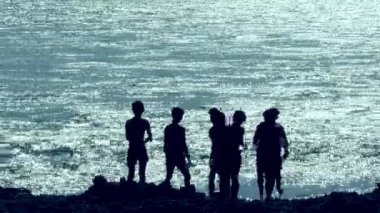 Rishikesh, Hindistan 24 Ocak 2025: Rishikesh 'teki Triveni Ghaat' ta Ganj Nehri 'nin kıyısında bir siluet duruyor, bir yönü işaret ederek, heyecanı işaret ediyor..