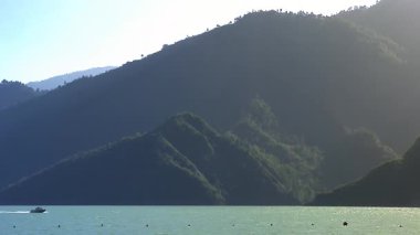 Mavi gölde heyecanlı bir sürat teknesi gezisi arka planda yeşil ağaçlarla dolu dağlarla zenginleşir..