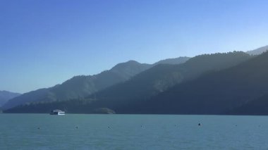 Bu zaman dilimi gölde yüzen bir oteli yakalıyor, etrafındaki dağlardan yükselen dumanlar yavaşça yükseliyor..