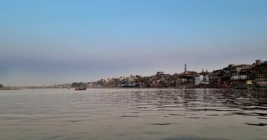 Tekneler Yamuna Nehri 'ni geçiyor, Mathura' nın ufuk çizgisi göz kamaştırıcı bir zemin görevi görüyor..