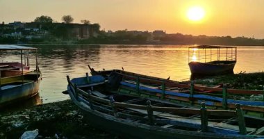 Mathura 'da günbatımı, Yamuna Nehri' nin üzerinde sıcak bir parıltı yayar. Teknelerin kenetlendiği ve kuşların güvertelerinde dolaştığı yerde..