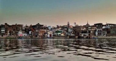 Akşam manzarası, Yamuna Nehri 'nden geçen Mathura siluetini yakalıyor. Gemiler geçiyor ve gökyüzü sıcak renklerle boyanıyor..