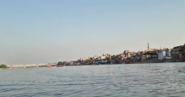 Mathura, Hindistan - 18 Mayıs 2025: Mathura Yamuna Nehri Ghat 'inde yaşayanlar, nehirde yelken açan tekneler ve diğer tarafta görünen şehir.