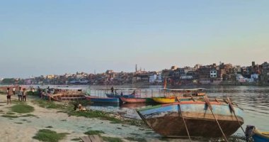 Mathura, Hindistan - 18 Mayıs 2025: İnsanlar Mathura Yamuna Nehri Ghat 'inde çeşitli görevlerde bulunuyorlar, yerel yaşam tarzlarını yansıtan tekneler tamir ediliyor..