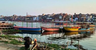 Mathura, Hindistan - 18 Mayıs 2025: Mathura 'daki Yamuna Nehri' nin kenarlarında çöp hatları kirliliğe yol açarken, tekneler yakınlarda park halindeyken, aktivite ve ihmal ikiliğini yansıtıyor..
