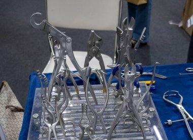 Teftiş için masanın üzerinde klempler ve tutucular da dahil olmak üzere çeşitli tıbbi cerrahi aletler sergilenmektedir..