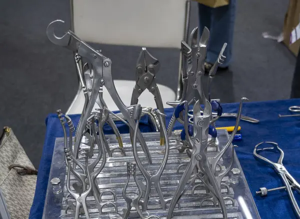 Teftiş için masanın üzerinde klempler ve tutucular da dahil olmak üzere çeşitli tıbbi cerrahi aletler sergilenmektedir..